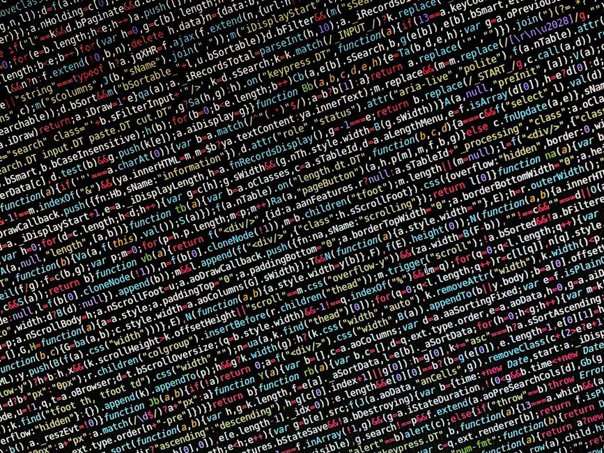 Close-up image of a computer screen displaying a dense layer of colorful programming code, including HTML, JavaScript, and CSS snippets. The code features various tags, functions, variables, and synta